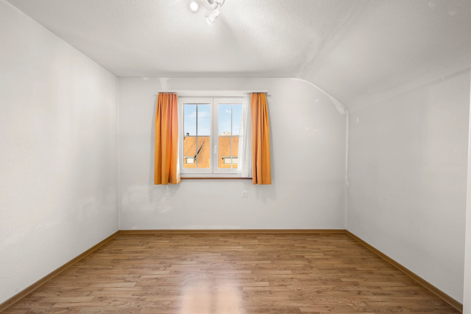 pièce vide avec plancher de bois, plafond voûté, et lumière naturelle