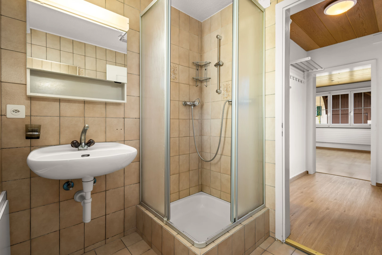 salle de bain avec vasque, douche, carrelage, mur carrelé, et plancher de bois