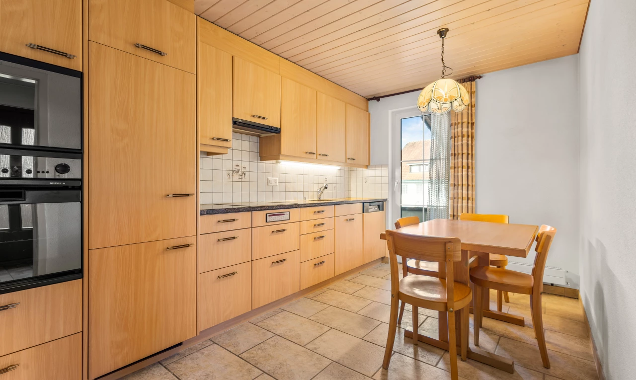 kitchen with tasteful backsplash, light brown cabinetry, light tile floors, decorative light fixtures, and a notable chandelier