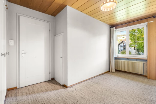 pièce vide avec lumière naturelle, plafond de bois, radiateur, et moquette