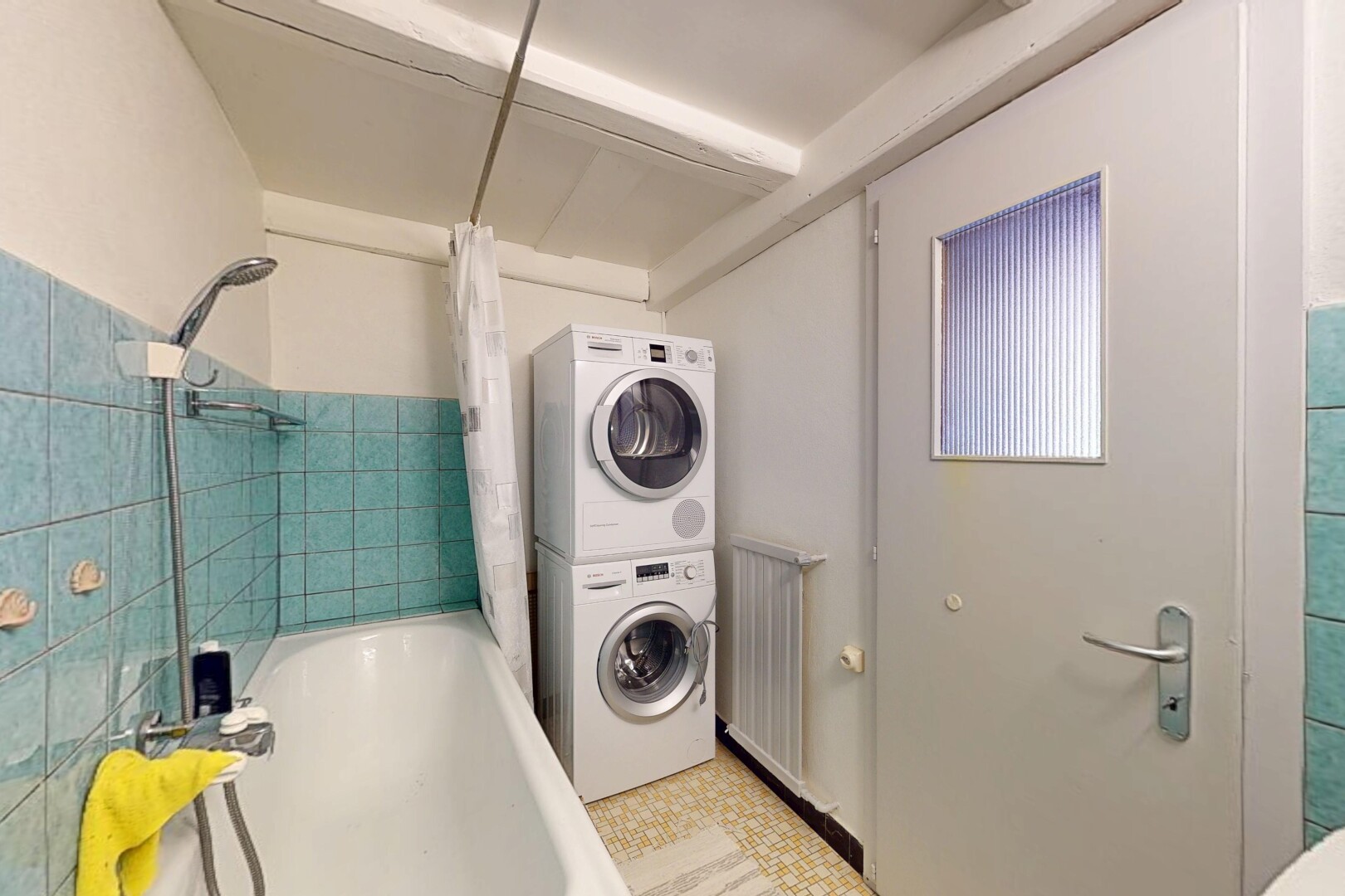 buanderie avec inside property, cloison sèche, drywall, lave-linge et sèche-linge superposés, et mur en carrelage