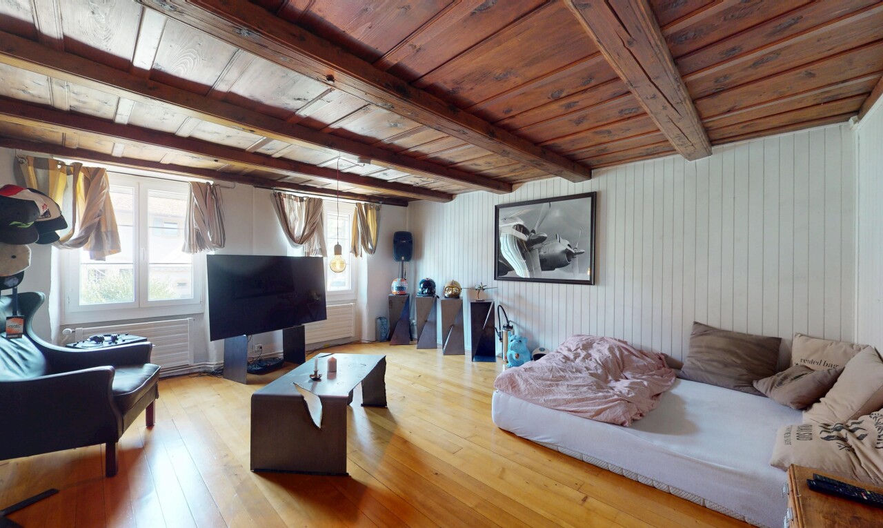 salon avec plafond à poutres, beamed ceiling, télévision, sol en finition bois, et wood finish floor