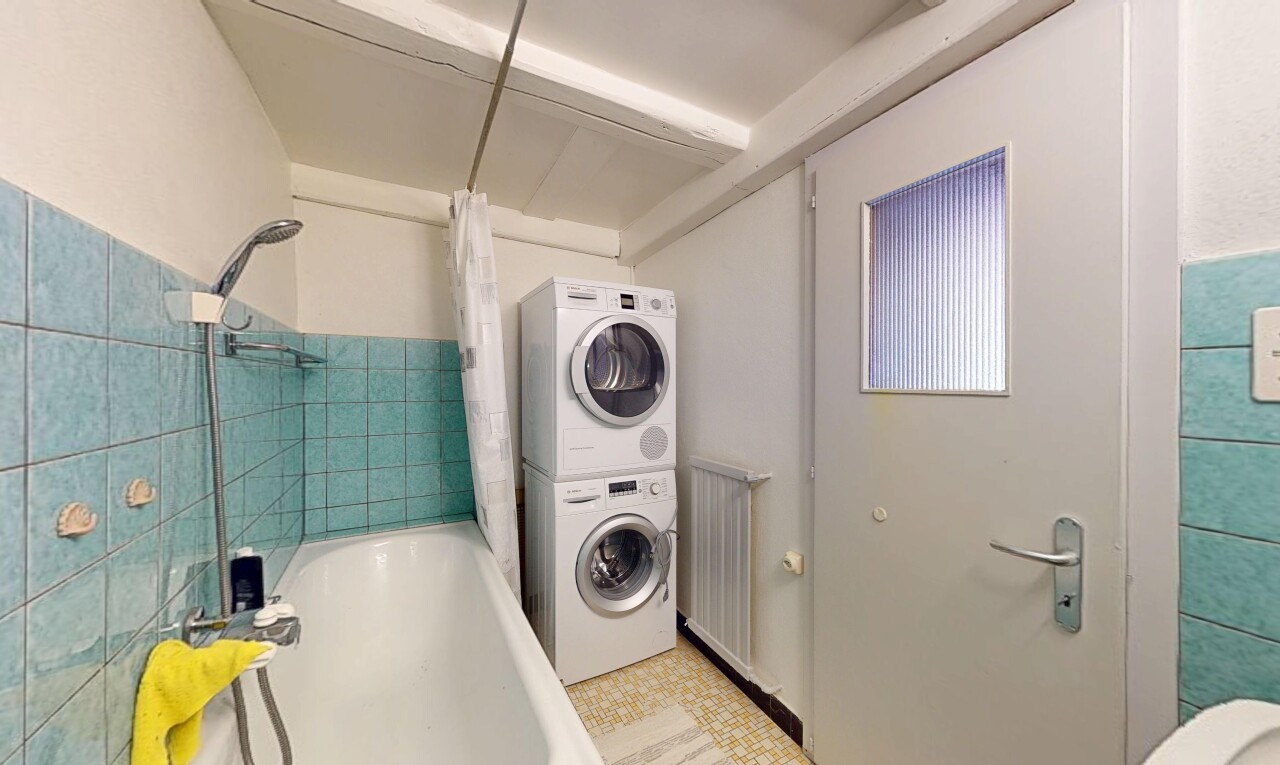 buanderie avec inside property, cloison sèche, drywall, lave-linge et sèche-linge superposés, et mur en carrelage