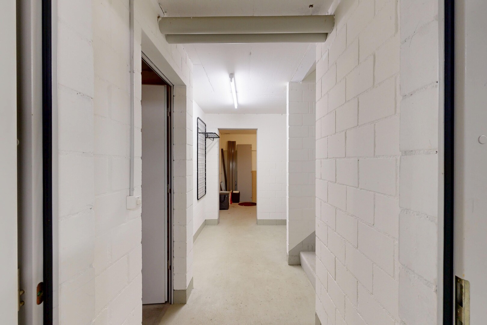 couloir avec mur en blocs de béton, concrete block wall, inside property, sol en béton, et concrete floor