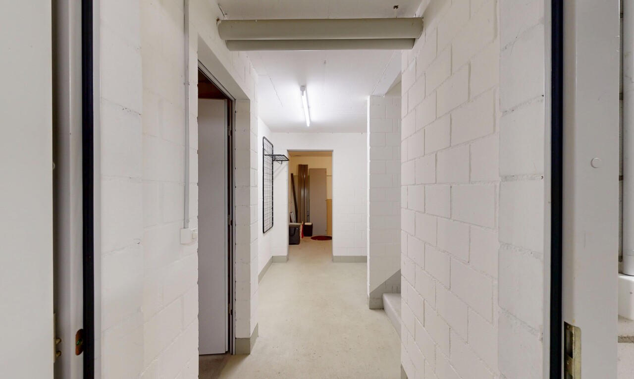 couloir avec mur en blocs de béton, concrete block wall, inside property, sol en béton, et concrete floor