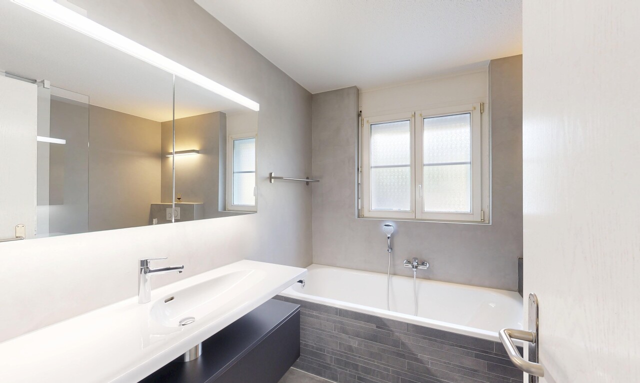 salle de bains avec salle de bain complète, miroir, lavabo (ou coiffeuse selon le contexte), bain, et lumière naturelle