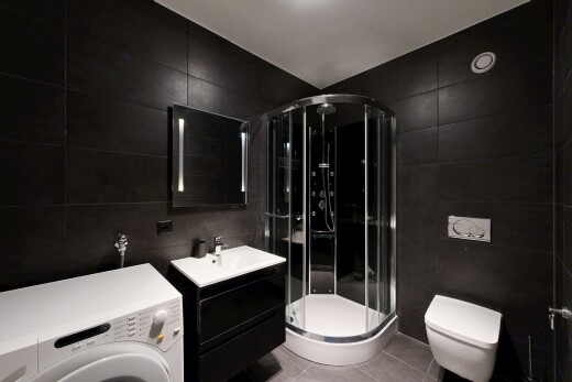 salle de bains avec tile wall, mur en carrelage, lave-linge et sèche-linge, lavabo (ou coiffeuse selon le contexte), et light floor