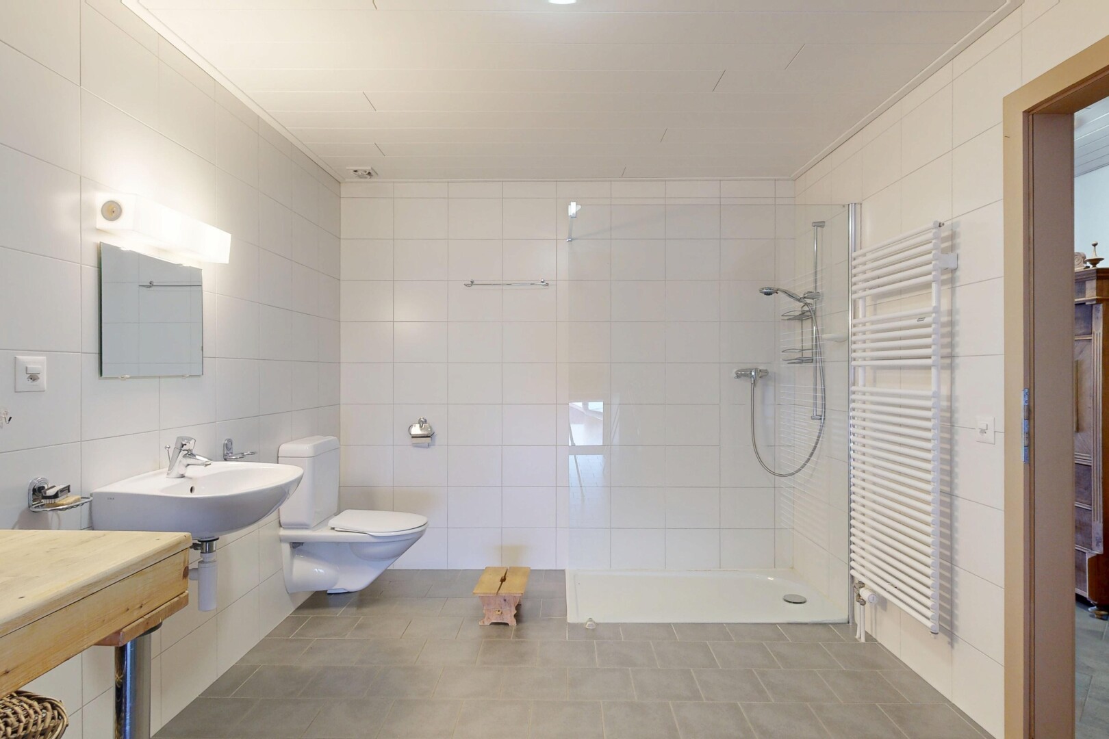 full bathroom featuring a towel warming rack, radiator heating unit, tiled shower, tile walls, and ornamental molding