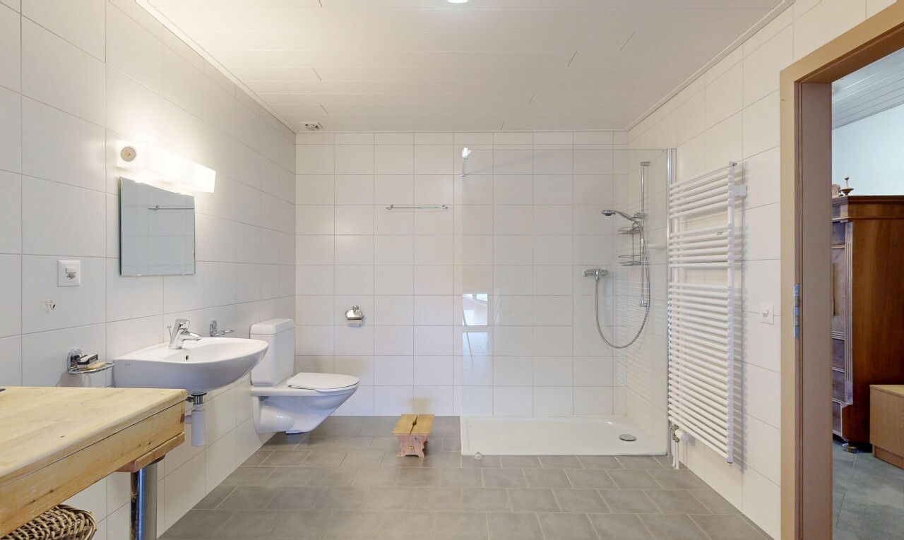 full bathroom featuring a towel warming rack, radiator heating unit, tiled shower, tile walls, and ornamental molding