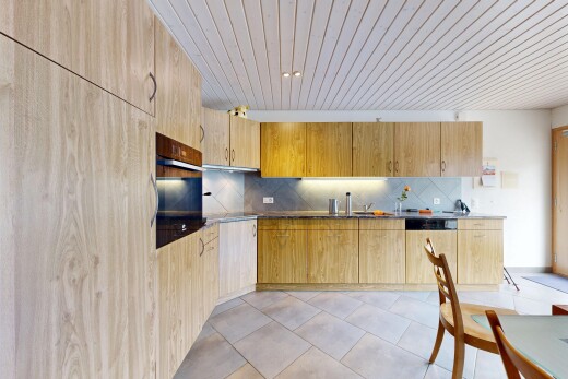 kitchen with light wood finish cabinets, oven, dark countertops, dishwasher, and backsplash