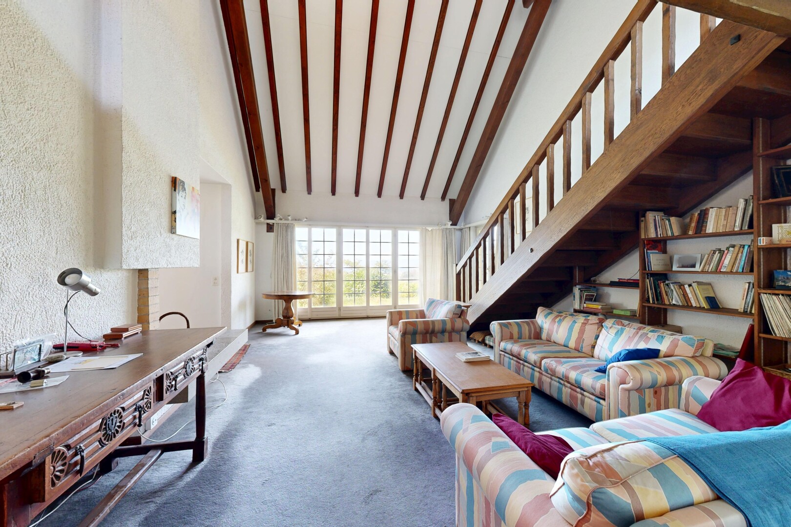 salon avec escaliers, high ceiling, plafond haut, carpet, et moquette