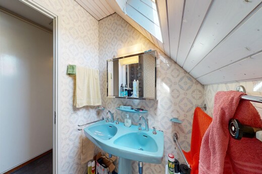 bathroom featuring wallpapered walls and lofted ceiling