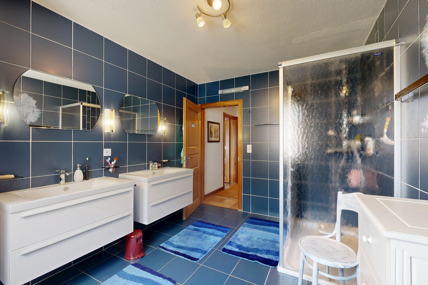 salle de bains avec mur en carrelage, tile wall, salle de bain complète, miroir, et deux lavabos simples
