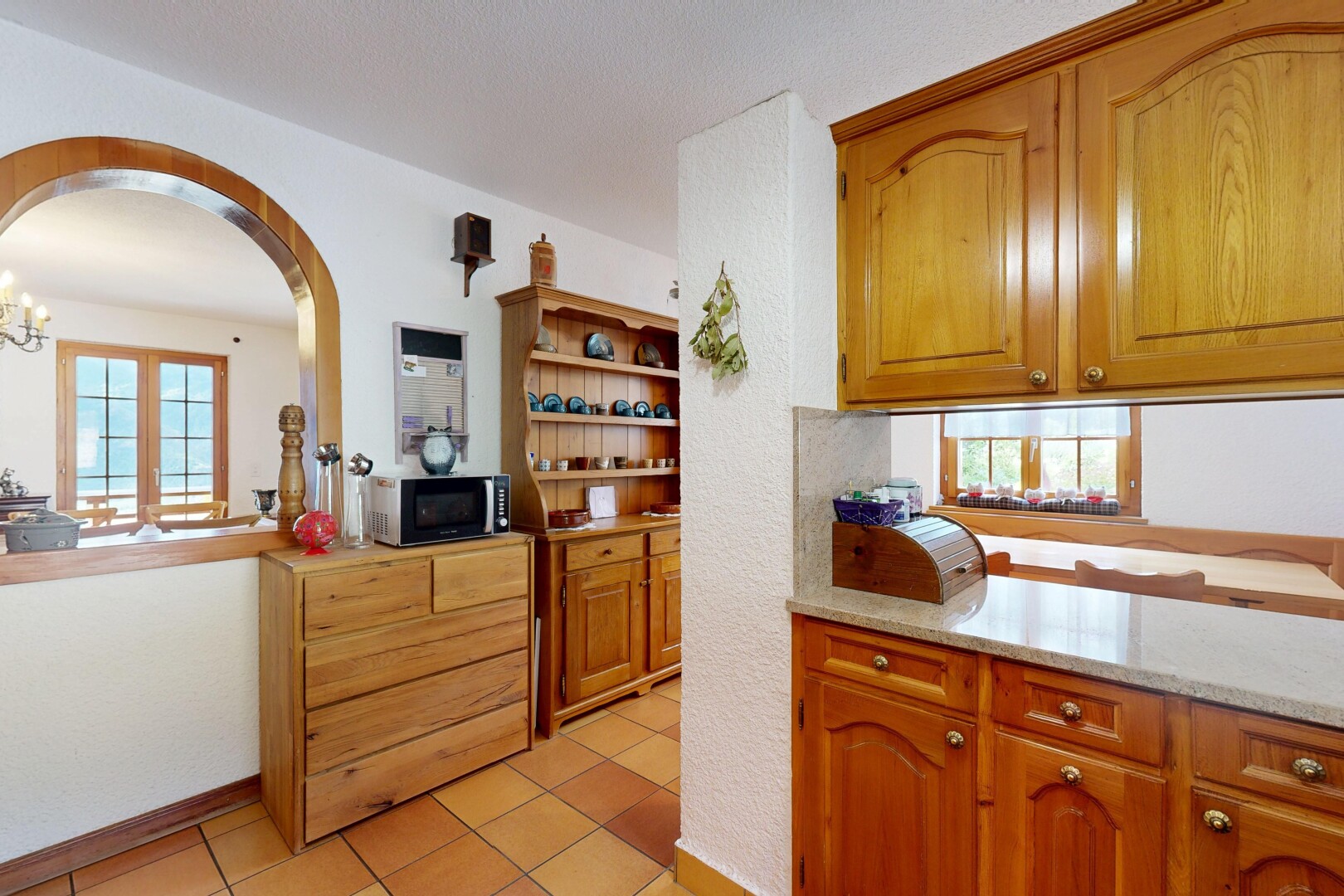 cuisine avec fenêtre de service, pass through window, light countertops, armoires en arc, et arched cabinets