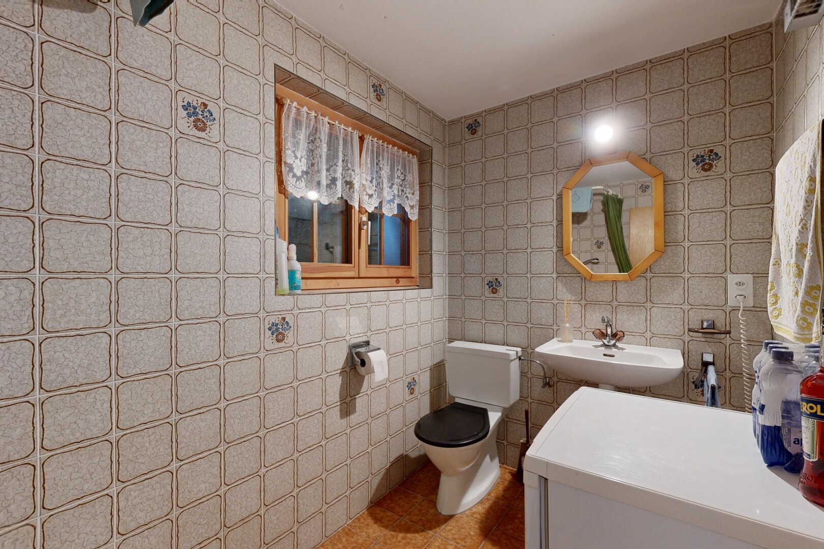salle de bains avec miroir, mur en carrelage, tile wall, toilette, et évier
