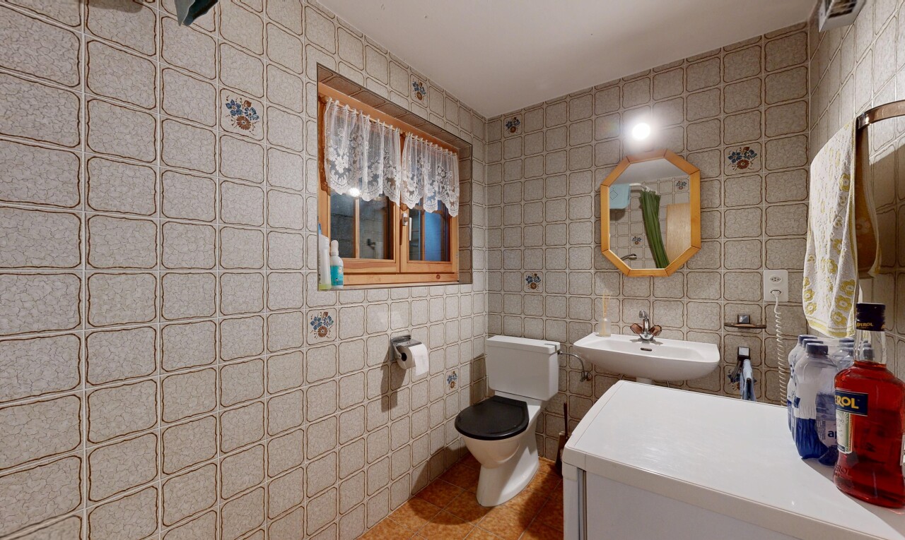 salle de bains avec miroir, mur en carrelage, tile wall, toilette, et évier