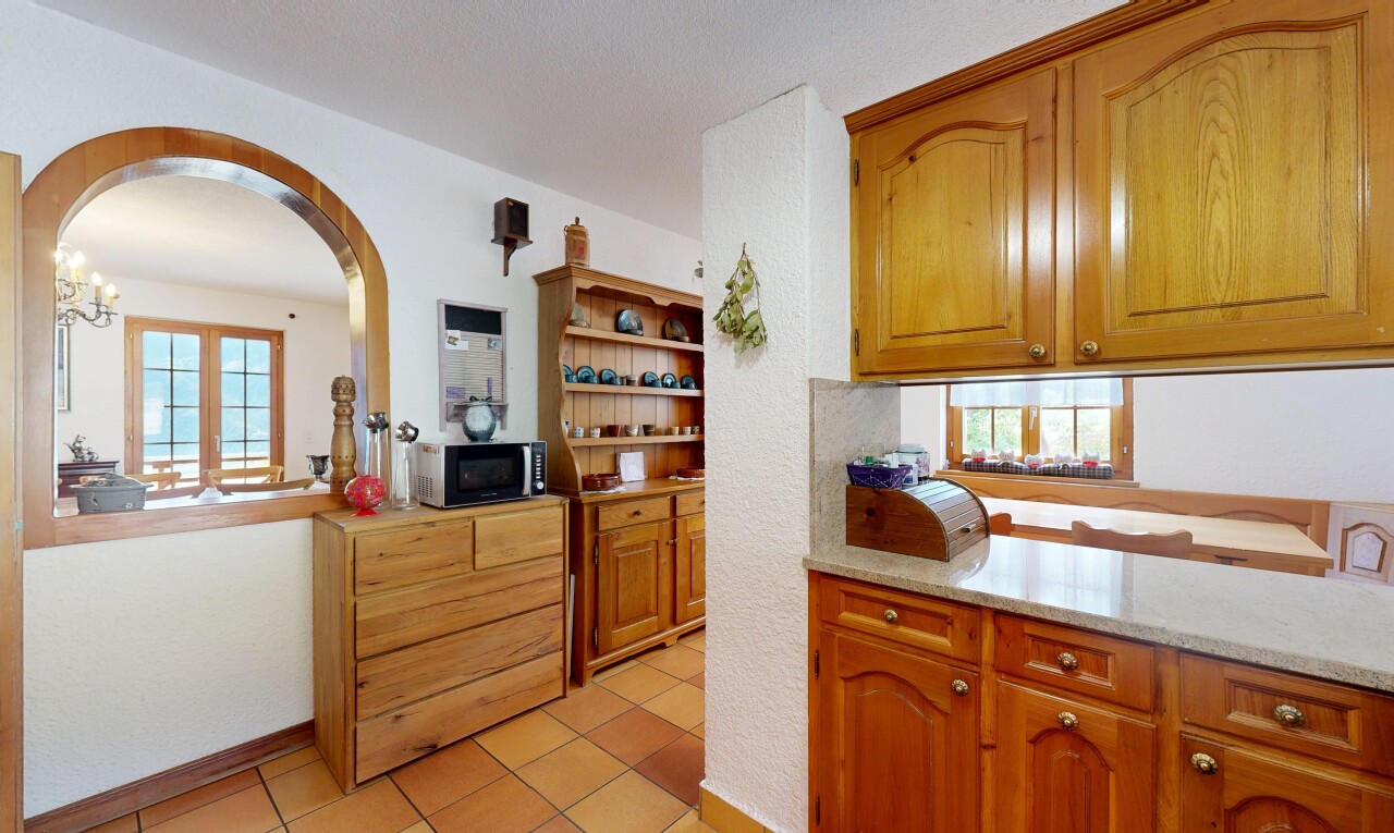 cuisine avec fenêtre de service, pass through window, light countertops, armoires en arc, et arched cabinets