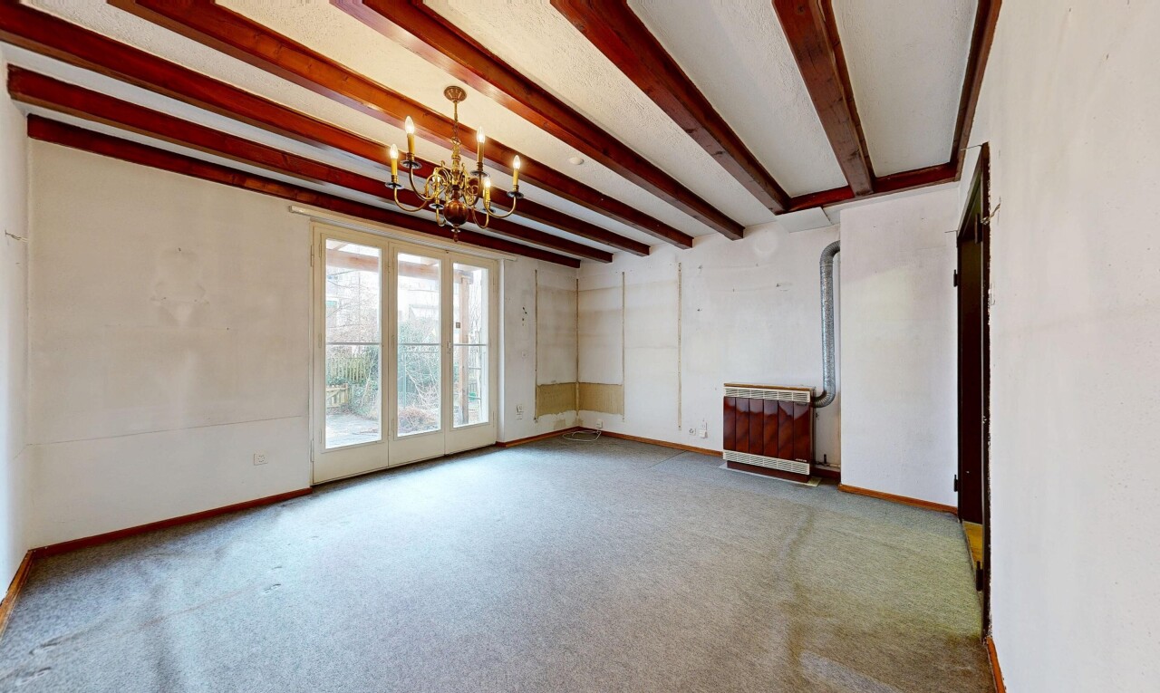 pièce vide avec inside property, plafond à poutres, beamed ceiling, lustre remarquable, et lumière naturelle