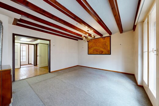 spare room with hanging lights, light colored carpet, and beam ceiling