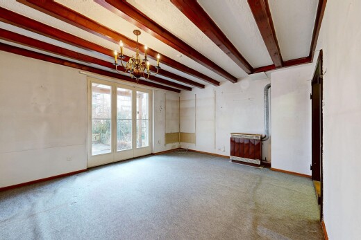 unfurnished room with beamed ceiling, a chandelier, and light carpet