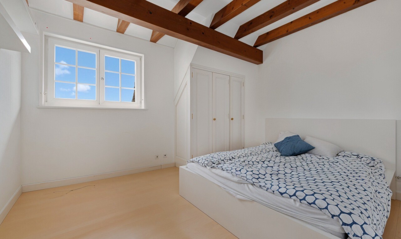 chambre avec drywall, cloison sèche, beamed ceiling, plafond à poutres, et natural light