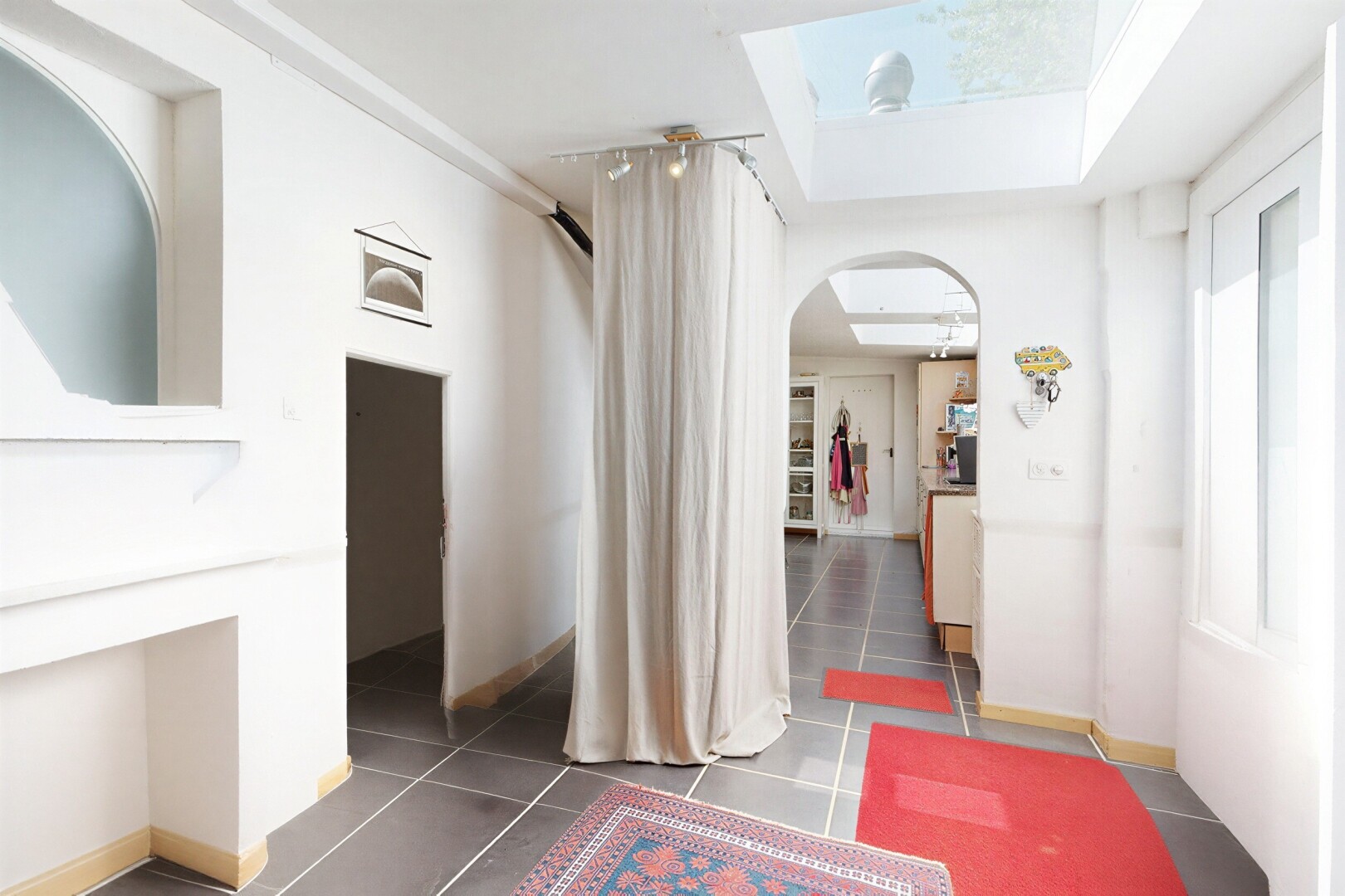 couloir avec passages en arc, cloison sèche, drywall, puits de lumière, et sol en carrelage