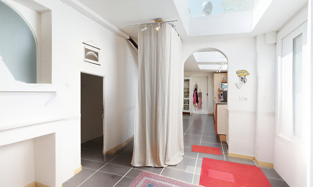 couloir avec passages en arc, cloison sèche, drywall, puits de lumière, et sol en carrelage