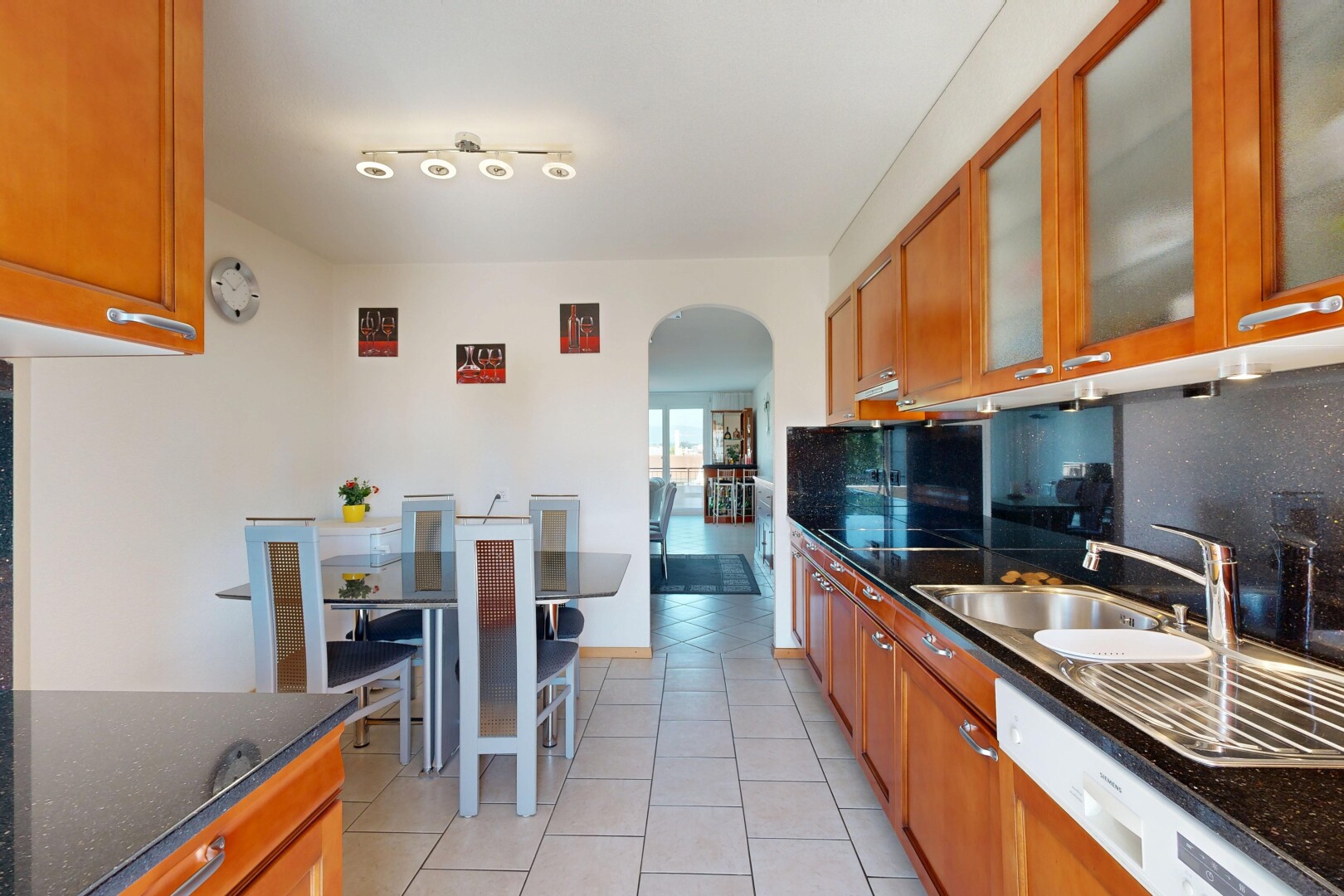 cuisine avec dark countertops, armoires marron moyen, medium brown cabinets, armoires avec insert en verre, et glass insert cabinets