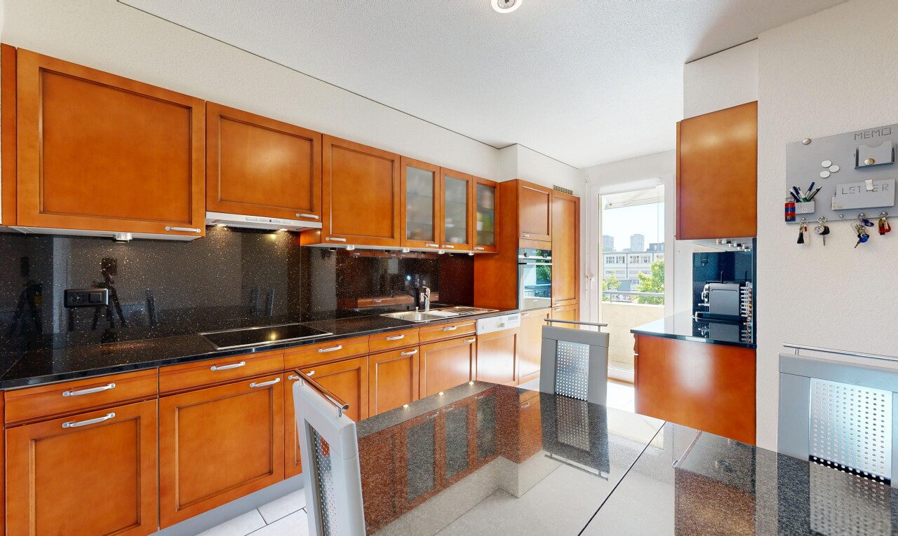 cuisine avec dark countertops, armoires avec insert en verre, glass insert cabinets, light floor, et backsplash