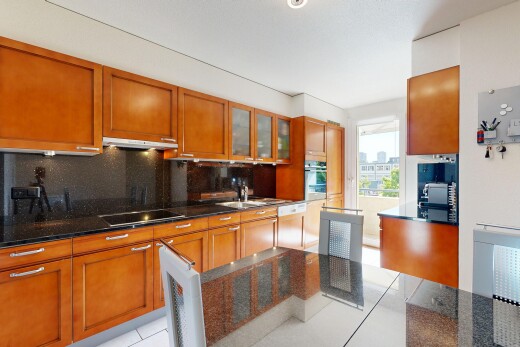 cuisine avec dark countertops, armoires avec insert en verre, glass insert cabinets, light floor, et backsplash