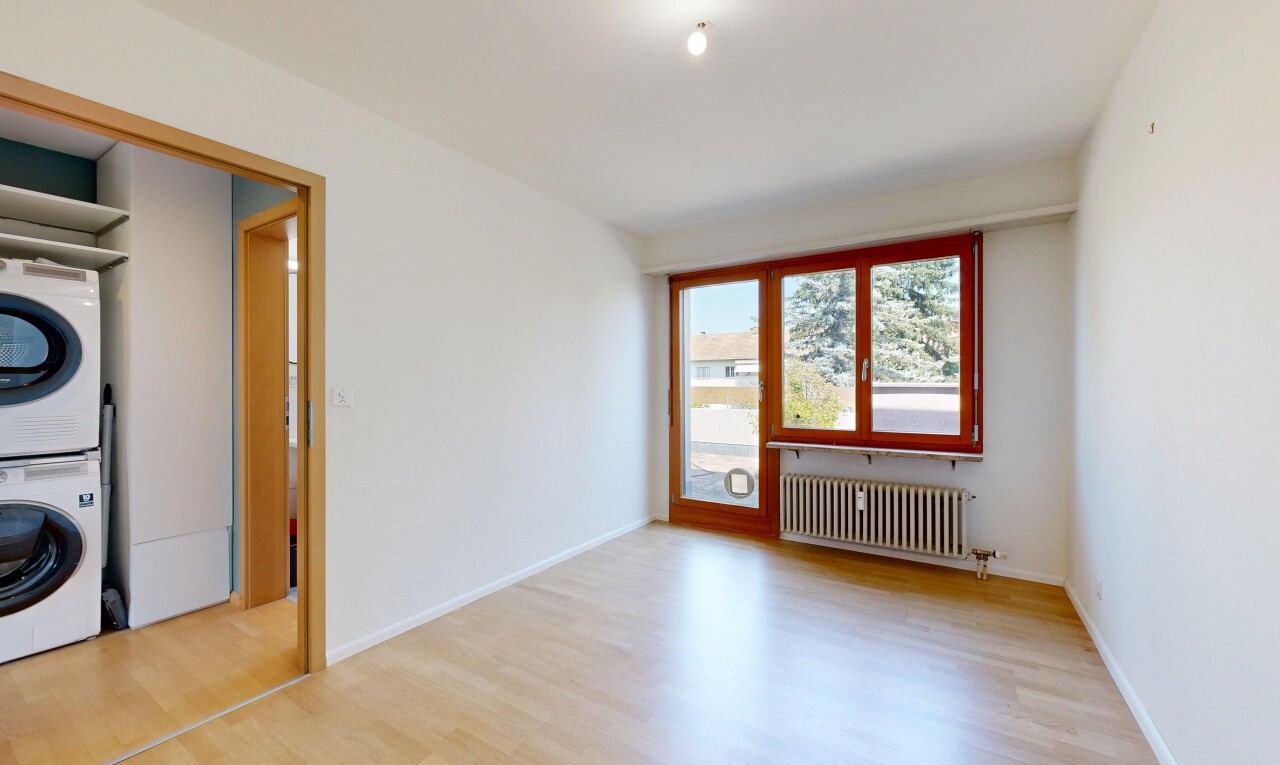 pièce vide avec wood finish floor, sol en finition bois, lave-linge et sèche-linge superposés, inside property, et radiateur