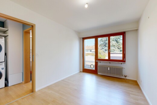 pièce vide avec wood finish floor, sol en finition bois, lave-linge et sèche-linge superposés, inside property, et radiateur