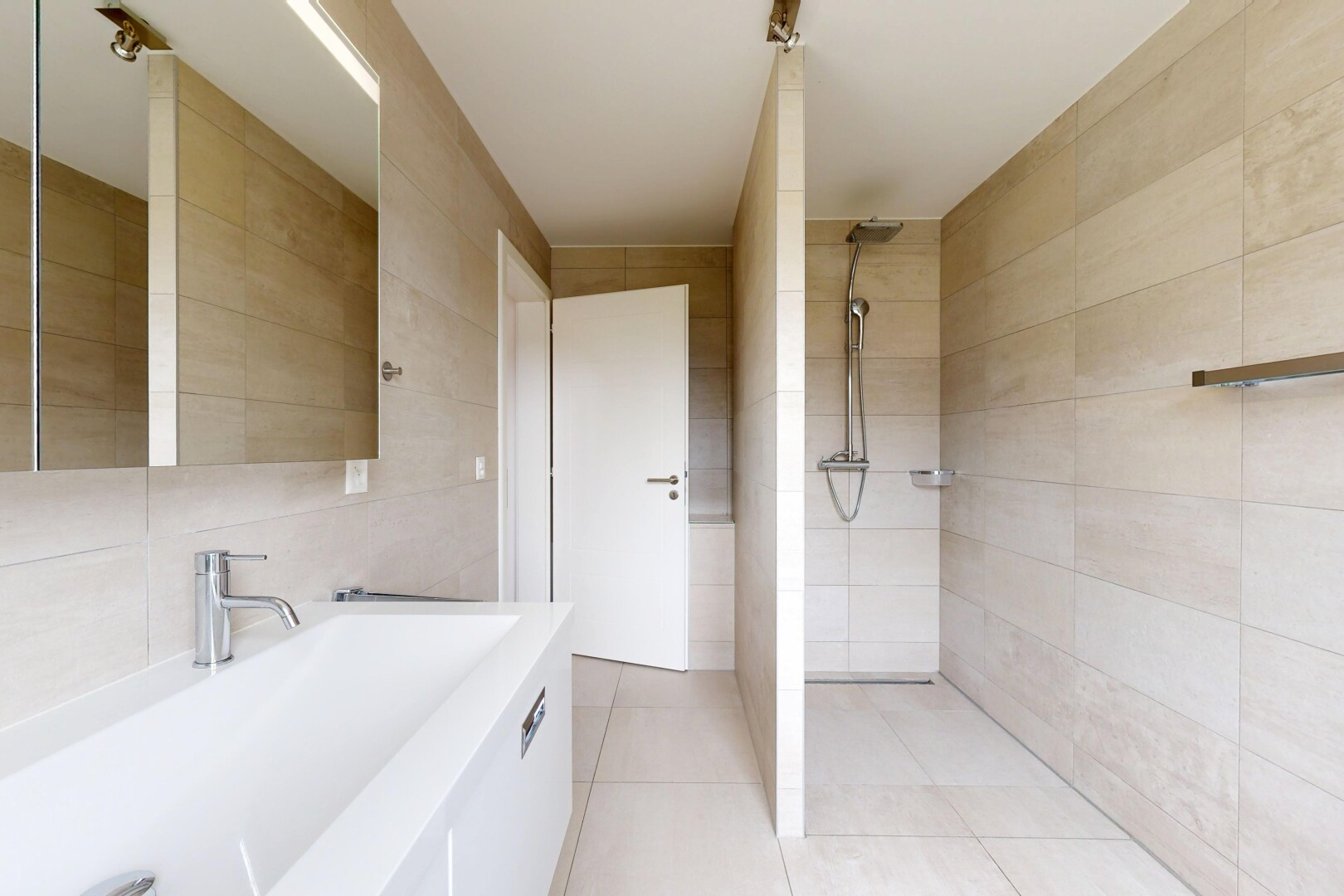 salle de bains avec mur en carrelage, tile wall, miroir, lavabo (ou coiffeuse selon le contexte), et douche
