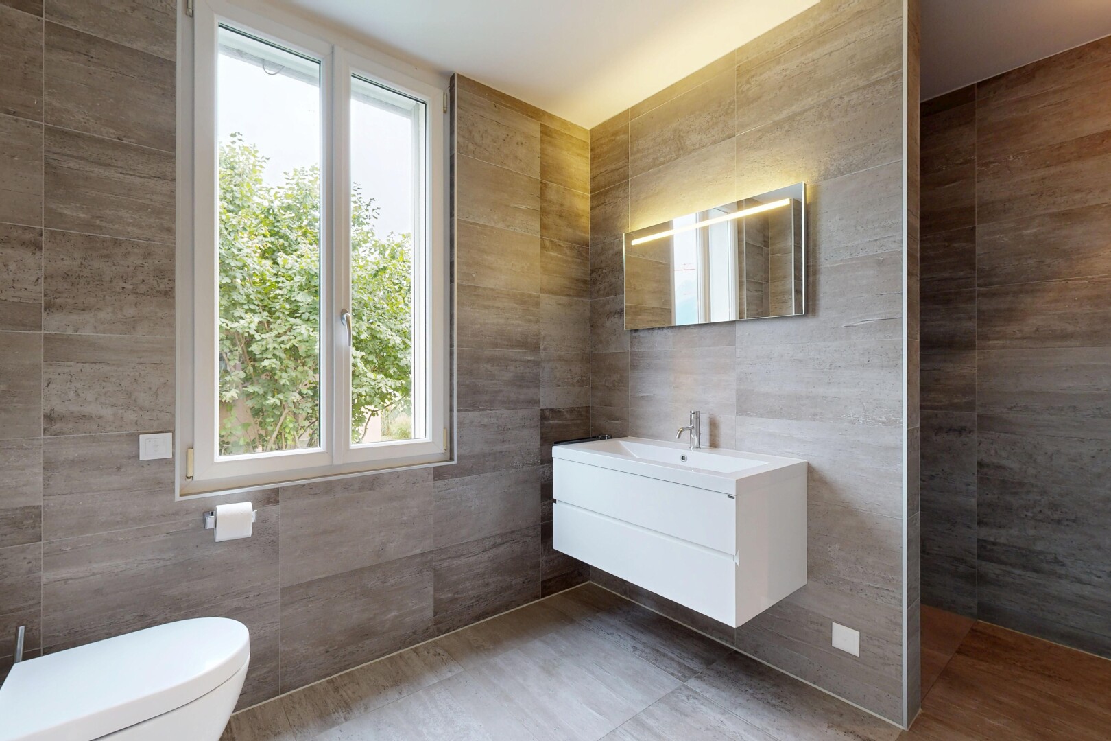 salle de bains avec mur en carrelage, tile wall, lavabo (ou coiffeuse selon le contexte), lumière naturelle, et natural light
