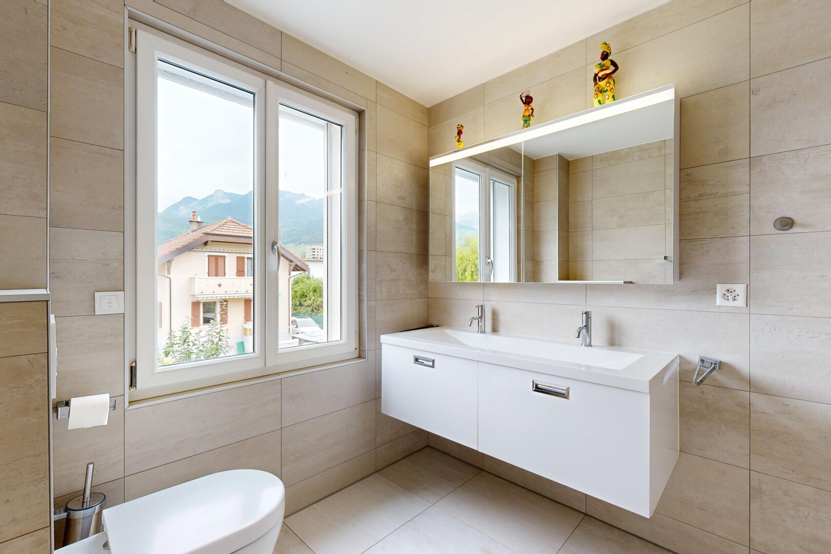 salle de bains avec mur en carrelage, tile wall, miroir, toilette, et lumière naturelle