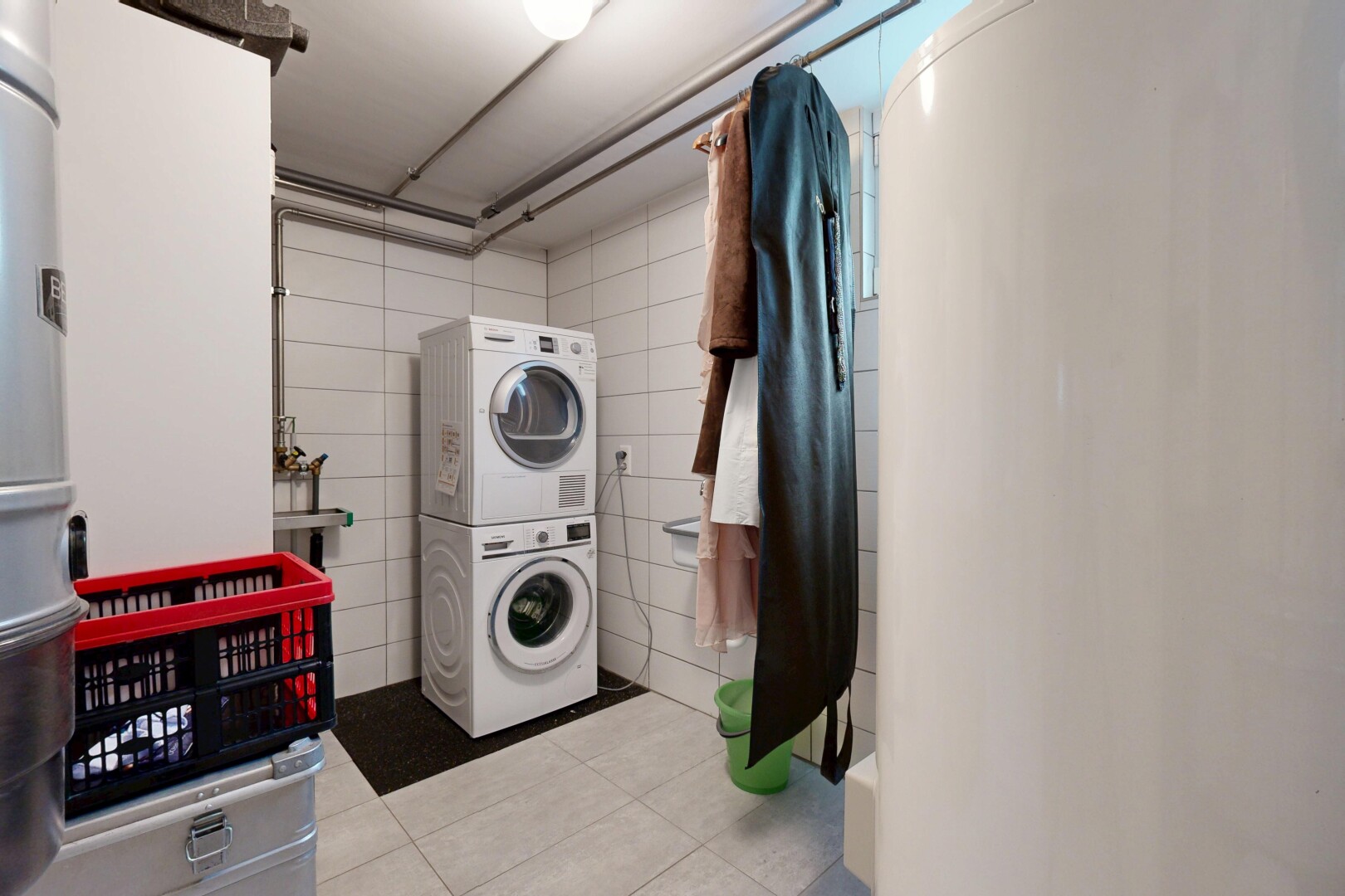 buanderie avec inside property, tile floor, sol en carrelage, lave-linge et sèche-linge superposés, et buanderie