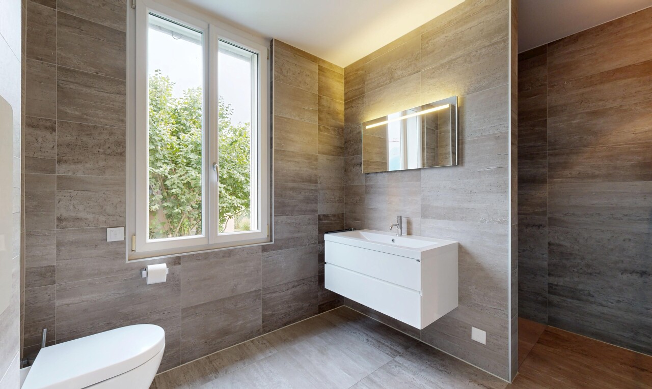 salle de bains avec mur en carrelage, tile wall, lavabo (ou coiffeuse selon le contexte), lumière naturelle, et natural light