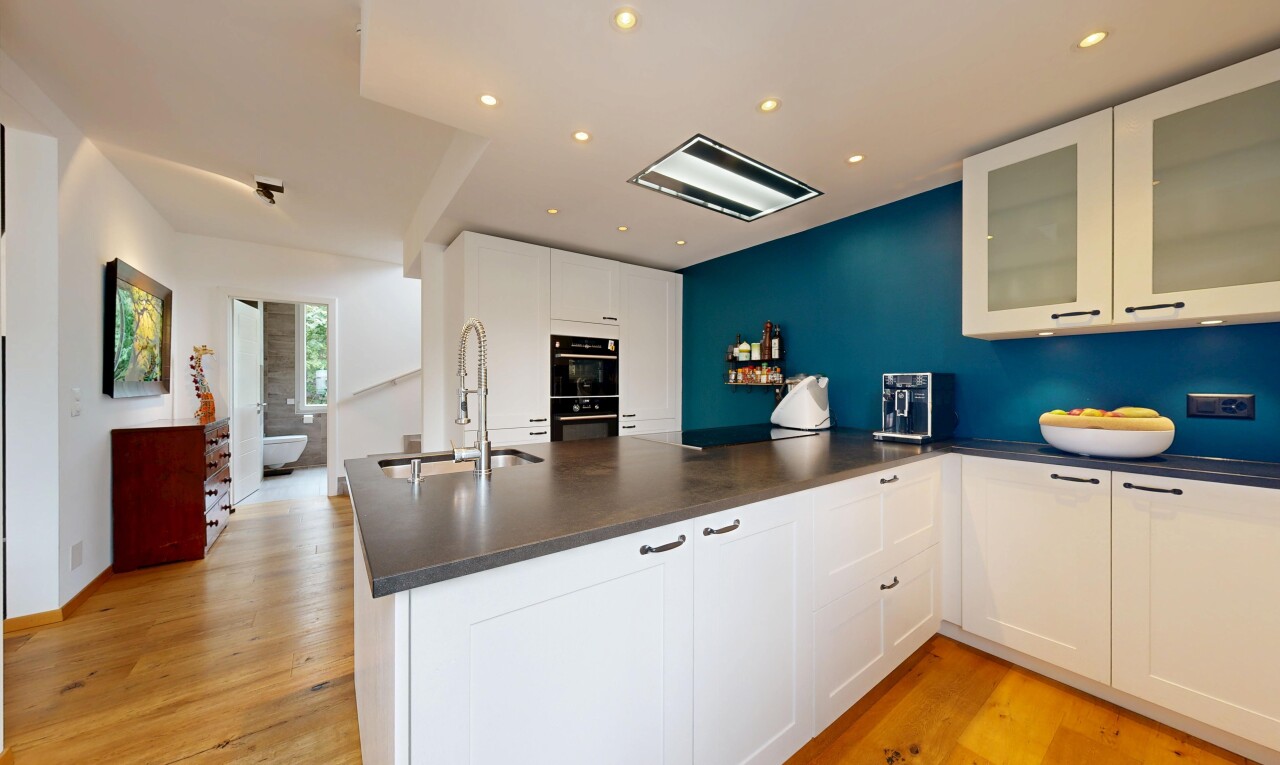 cuisine avec sol en finition bois, wood finish floor, armoires avec insert en verre, plans de travail, et lumière naturelle