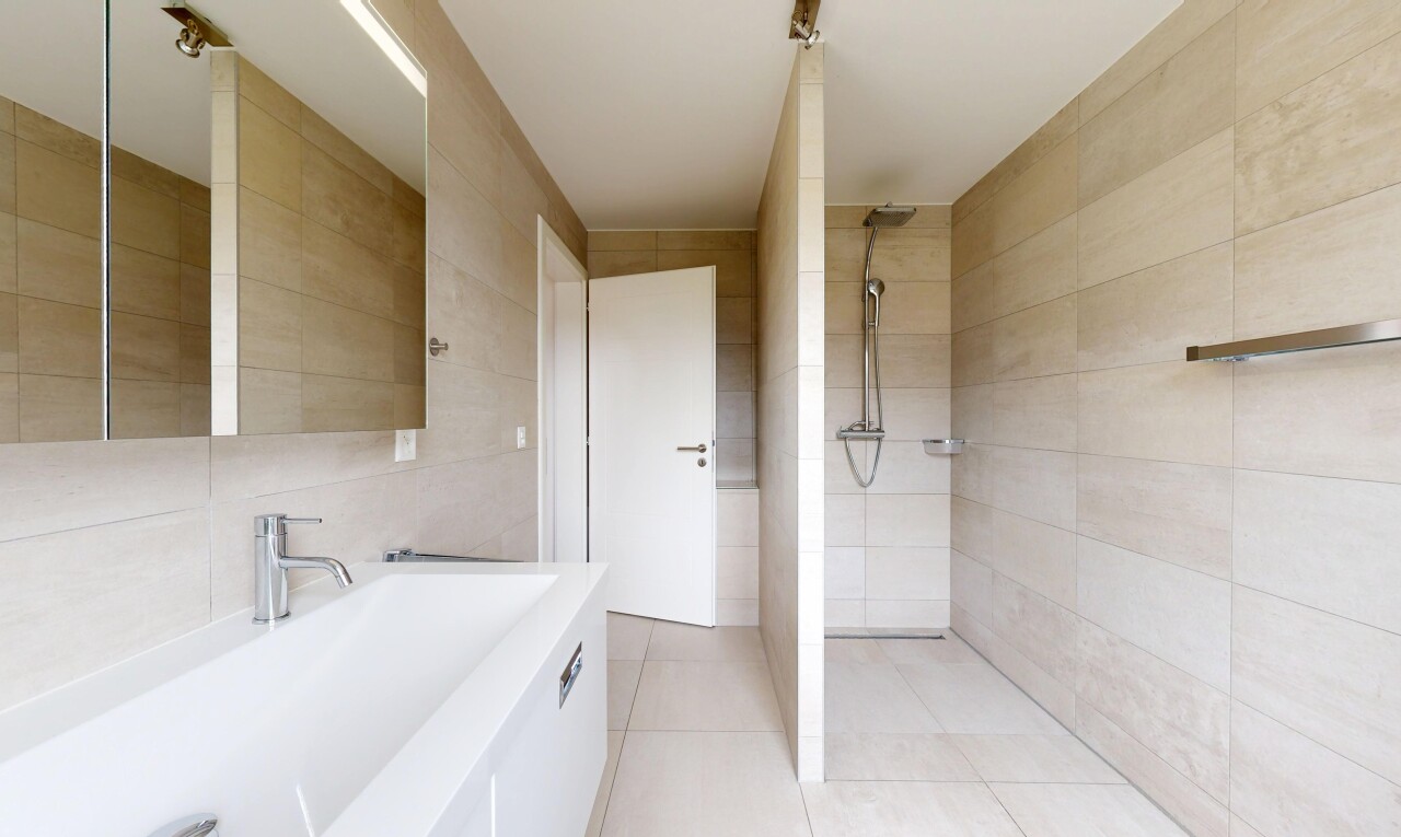 salle de bains avec mur en carrelage, tile wall, miroir, lavabo (ou coiffeuse selon le contexte), et douche