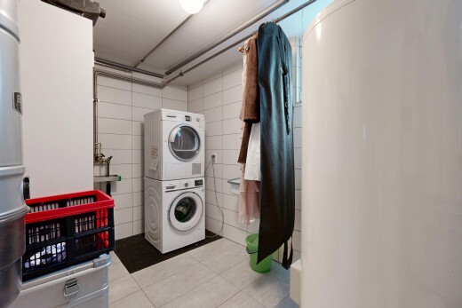 buanderie avec inside property, tile floor, sol en carrelage, lave-linge et sèche-linge superposés, et buanderie