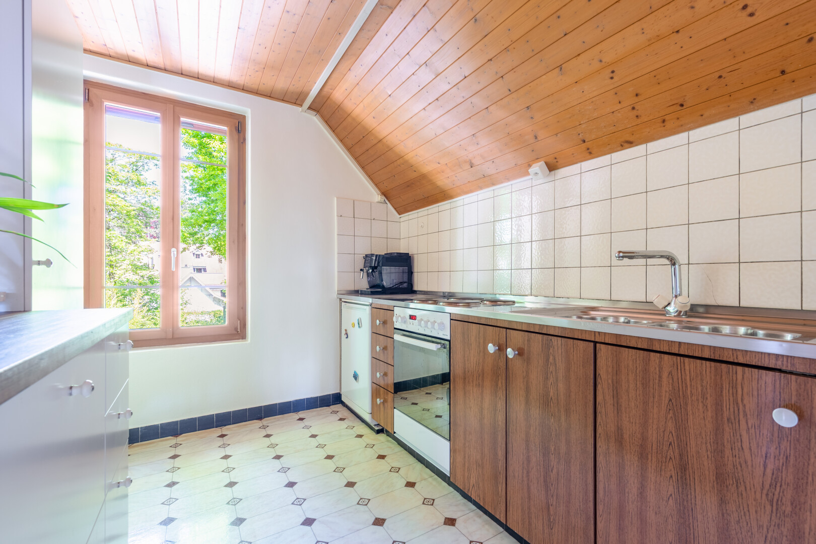 küche mit holzdecke, wood ceiling, mittelbraune schränke, waschbecken, und natürliches licht