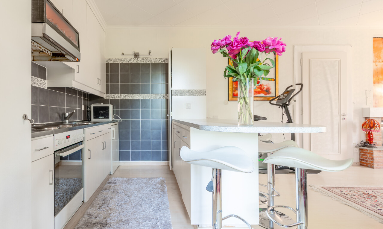 küche mit dunstabzugshaube, ofen, inside property, weiße schränke, und mikrowelle