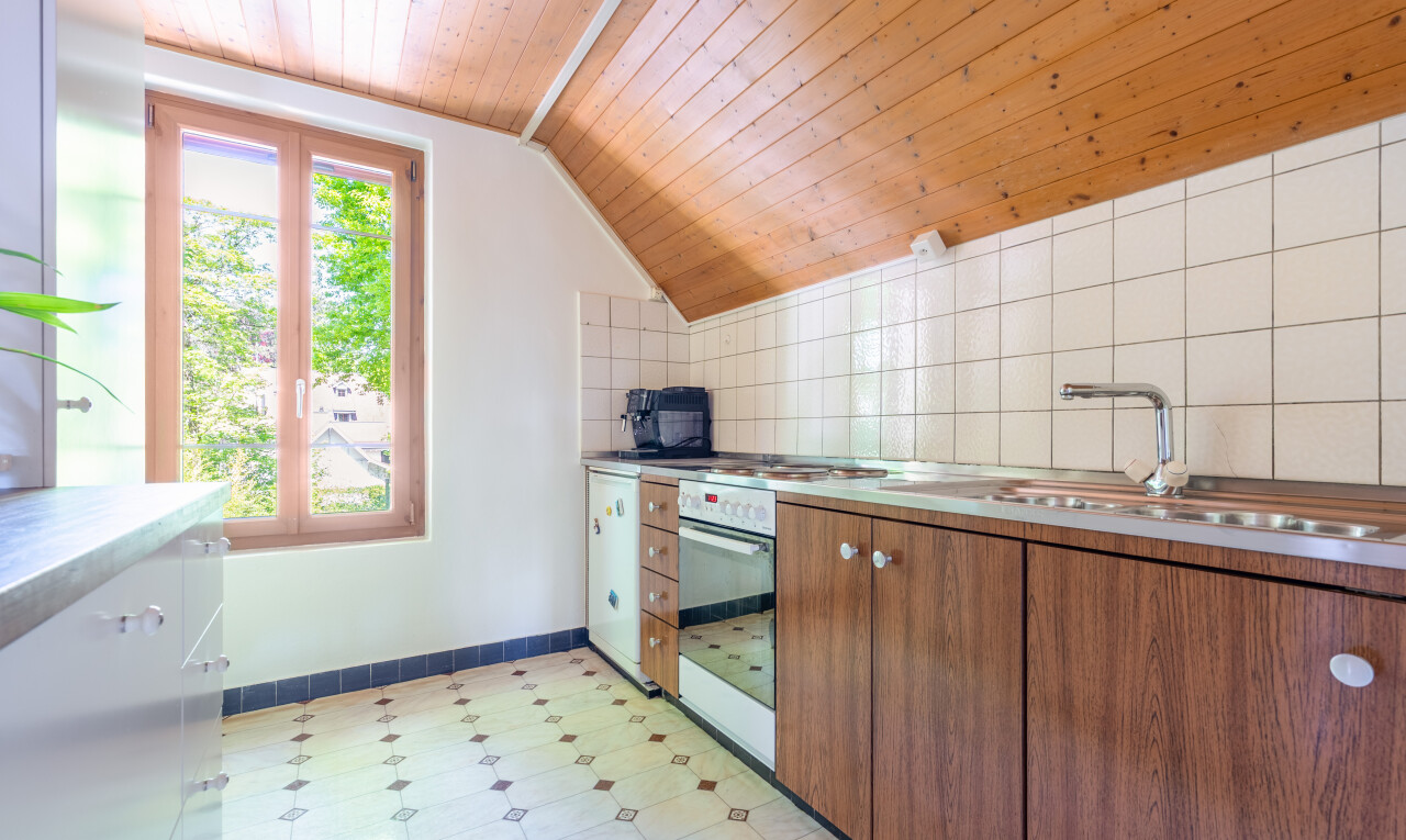 küche mit holzdecke, wood ceiling, mittelbraune schränke, waschbecken, und natürliches licht