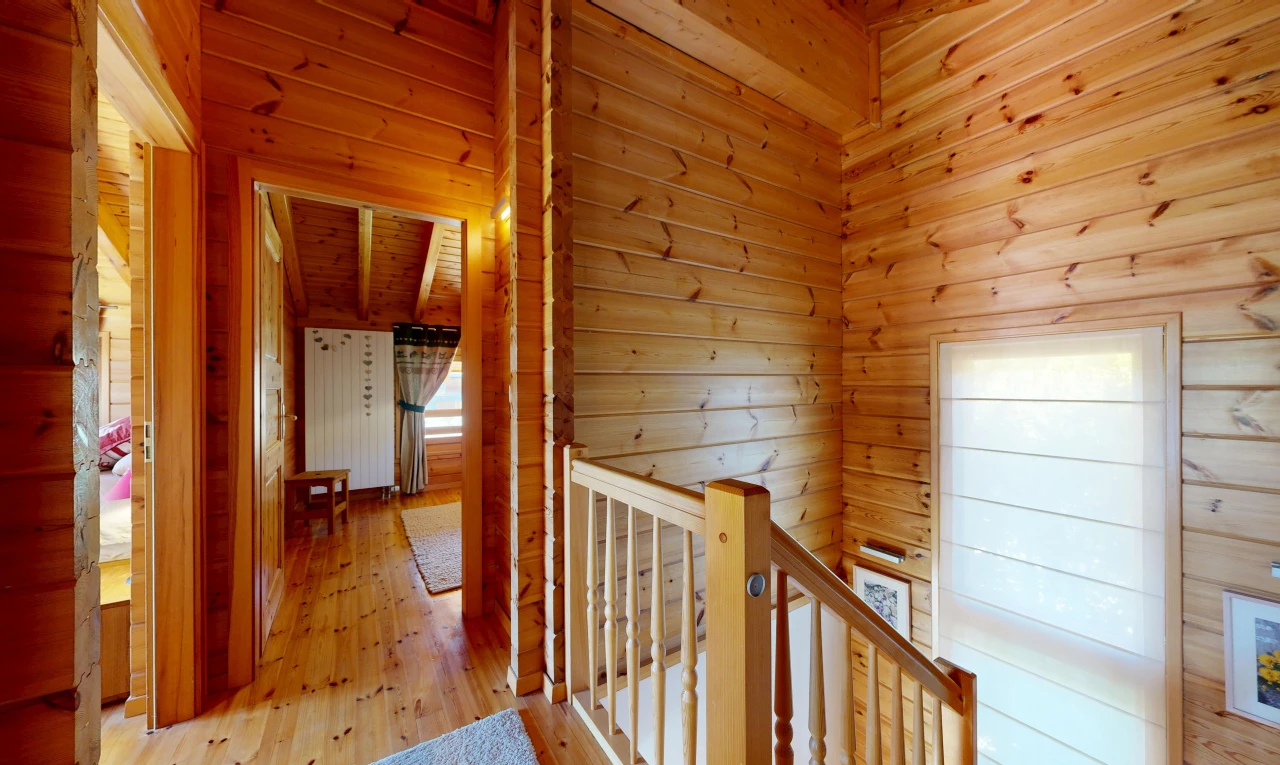 hallway featuring an upstairs landing, wooden walls, and hardwood / wood-style floors