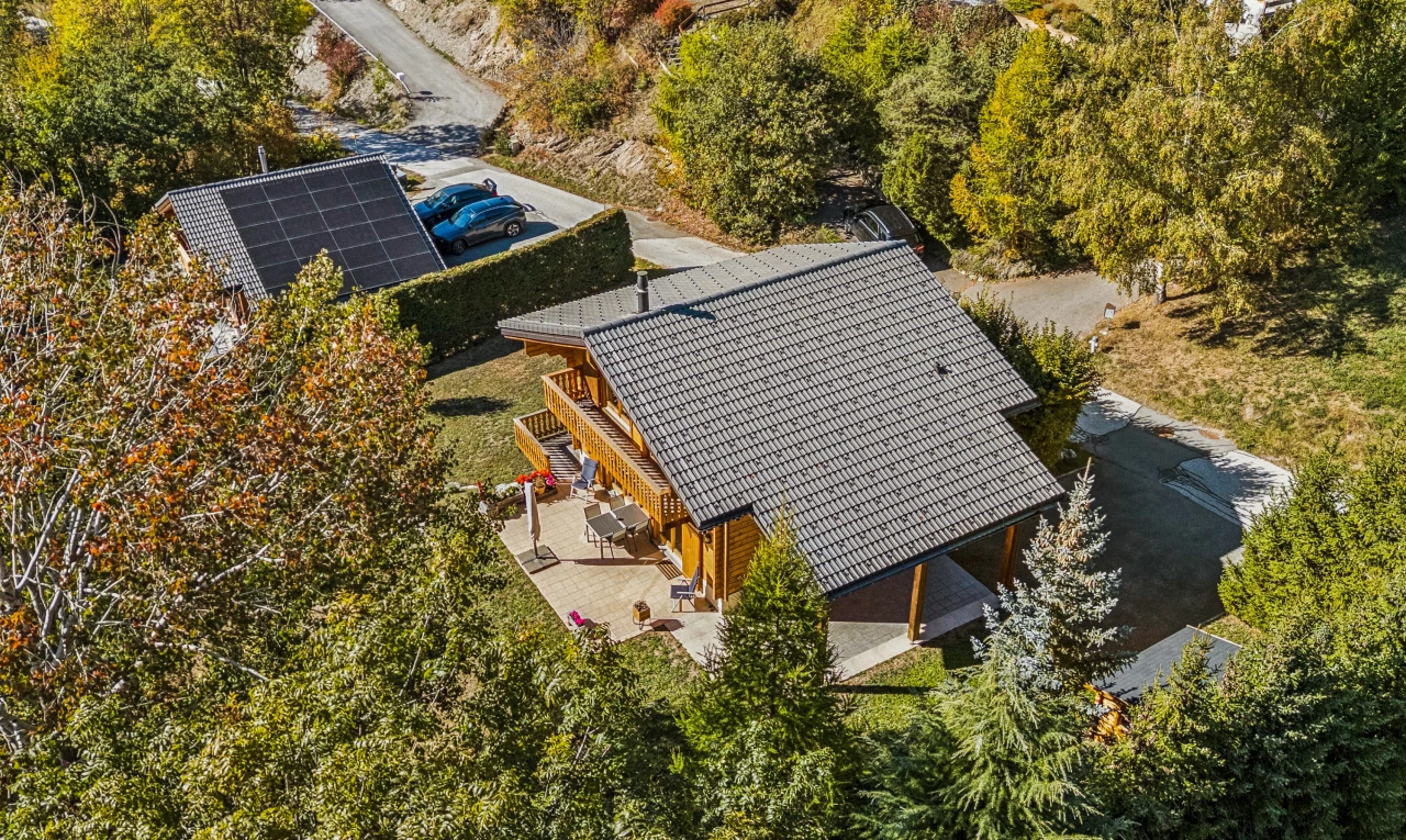 view of home with a patio, solar panels, and view of scattered trees