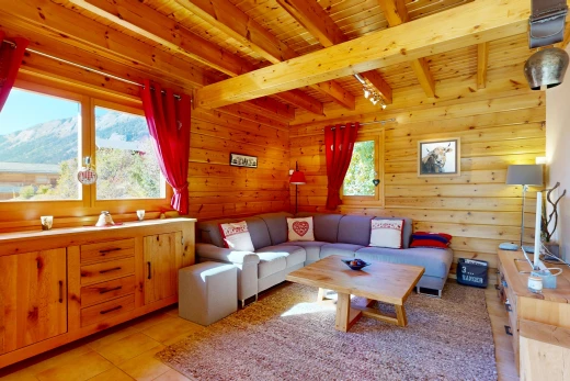living area with wooden walls, a mountain view, a wooden ceiling with exposed beams, and light tile patterned floors