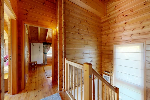 hallway featuring an upstairs landing, wooden walls, and hardwood / wood-style floors