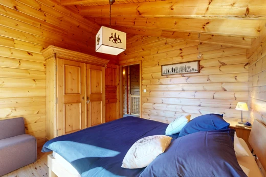 room / bedroom with wooden ceiling, lofted ceiling with beams, light wood finished floors, and wooden walls