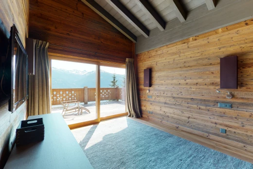 chambre à coucher avec poutres apparentes, lumière naturelle, plafond voûté, moquette, et télévision