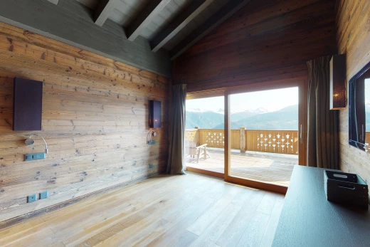 chambre vide avec plafond voûté, parquet, lumière naturelle, et poutres apparentes